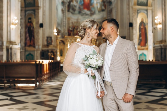 A bride and groom stand in a church